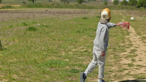 Child throwing plastic waste in a beautiful green field Stock Footage 332975443
