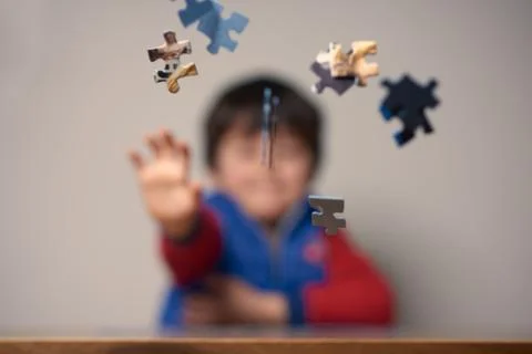 A CHILD THROWING PUZZLE PIECES Stock Photos
