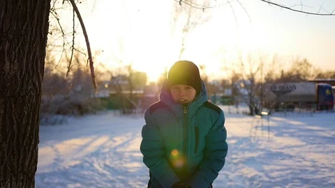 Child throwing snow over himself and enjoys it in winter park at sunset Vidéo 69909546