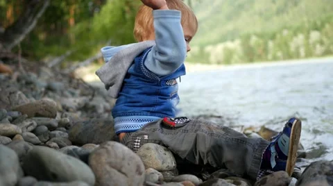 Child throwing stones into the river Видео 65938239