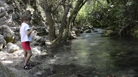Child throwing stones at a small river. Stock Footage 135605949