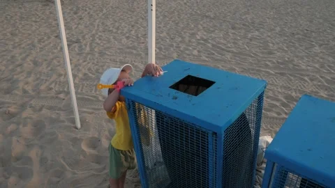 Child throws feather into trash can on beach Stock Footage 303499251