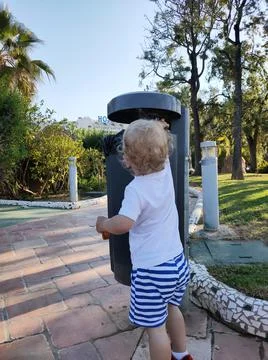 Child throws garbage in a trash can in the park Stock Photos