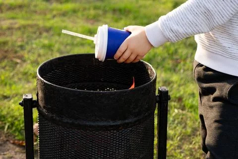 A child throws a plastic cup in the trash. Garbage recycling and plastic wa.. Stock Photos