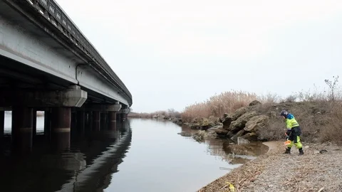 A child throws sand into the river and a beautiful sky Stock Footage 103352409