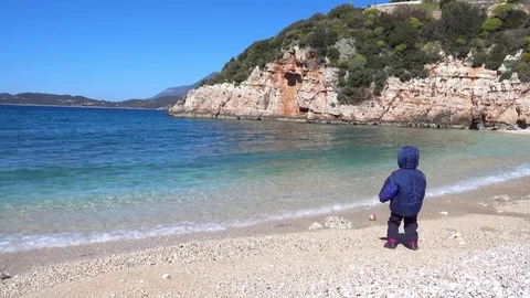 Child throws a stone to the winter sea Stock Footage 73771697