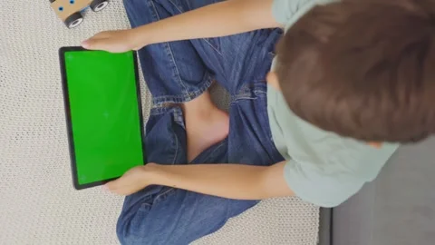 Child tilting to the left and right a tablet with green screen, top view Stock Footage 255510207