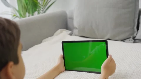 Child tilting to the left and right a tablet with green screen, side view Stock Footage 255511044