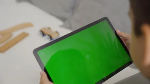 Child tilting to the left and right a tablet with green screen, side view Stock Footage 255511215