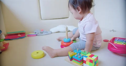 Child toddler girl is playing with a stack of colorful blocks. The blocks are ar 動画素材 267063278