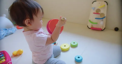 Child toddler girl is playing with a stack of colorful blocks. The blocks are ar Stock Footage 267063629