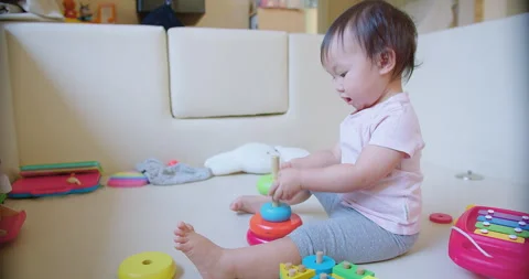 Child toddler girl is playing with a stack of colorful blocks. The blocks are ar Stock Footage 267073495