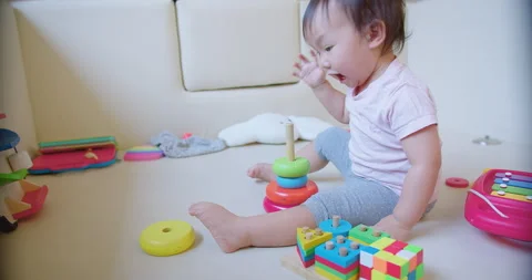 Child toddler girl is playing with a stack of colorful blocks. The blocks are ar Stock Footage 267073578