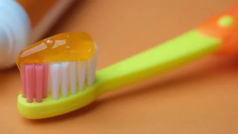 Child tooth brush and paste on orange background Stock Footage 166509549