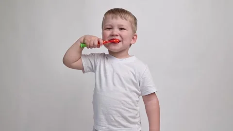 Child with a toothbrush on a white background diligently brushes his teeth close Stock Footage 242473950