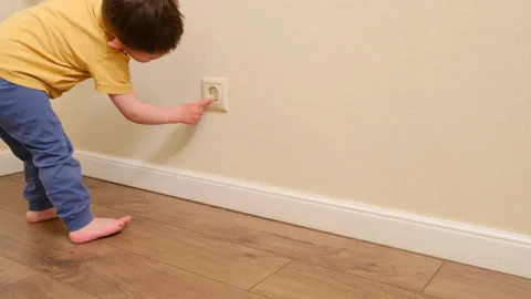 Child touching electrical wall outlet with finger. Dangerous home situation and Stockbeeldmateriaal 341855926