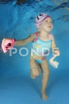 Child with a toy swim underwater in the pool Stock Photos