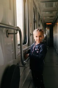 Child in train looking though train window on sunset Stock Photos