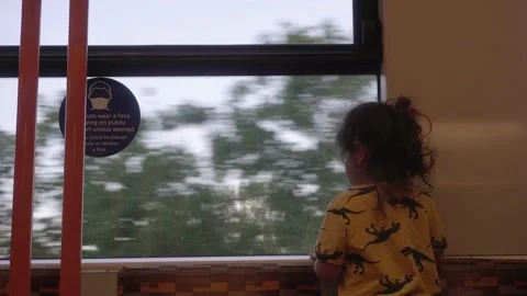 Child on train ride looking out the window during covid pandemic mask sign day Stock Footage 170721591