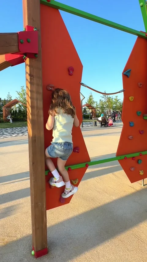Child tries to climb up an alpine grid in a park, but suddenly falls down Stock Footage 244949022
