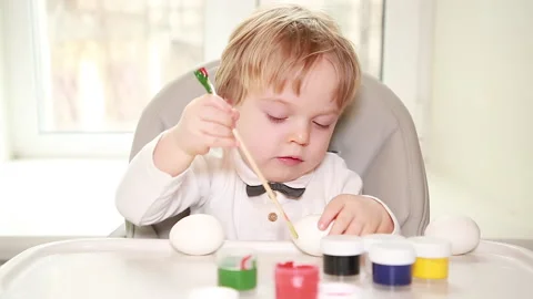 A child tries to paint Easter eggs Stock Footage 149847032