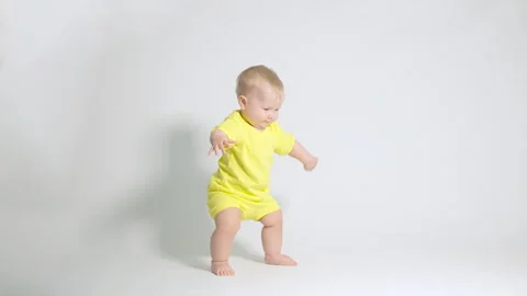 The child tries very hard to keep his balance when trying the first steps Video stock 244845439
