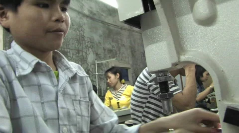 A child trying to fix a sewing machine with the help of a wench in a sweatshop Stockbeeldmateriaal 556686