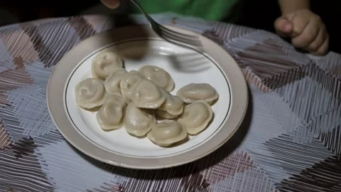 Child trying to take ravioli with fork in plate. close up. dumplings Stock Footage 297221838