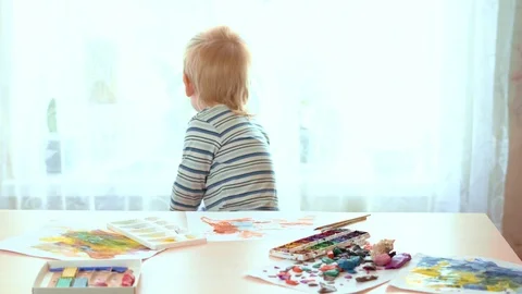 Child turned back window from the table with paints and paper clay, then leaves Stock Footage 129253549