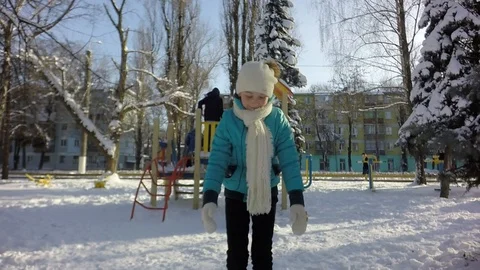 A child in a turquoise jacket blows snow from his hands. 库存影片 87543302