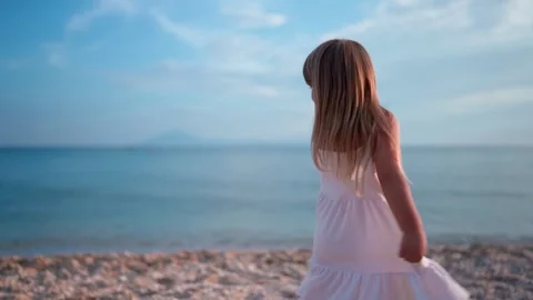 Child twirling on beach in soft sunlight Видео 341120048