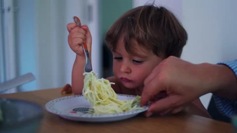 Child twirling spaghetti with fork at the kitchen table at home, focused se.. Stock Footage 340427977