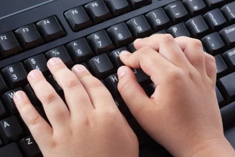 Child typing something on black computer keyboard Stock Photos