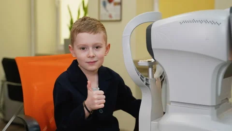 Child undergoing eye exam giving thumbs up at clinic Stock Footage 310806604
