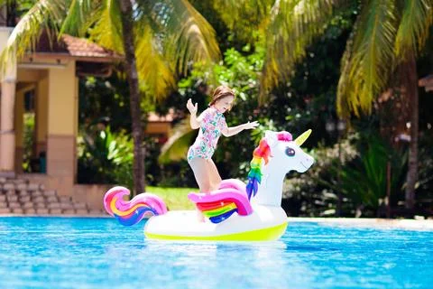 Child on unicorn float in swimming pool. Kids swim Stock Photos