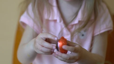 A child unpacks a chocolate Easter egg. Stock Footage