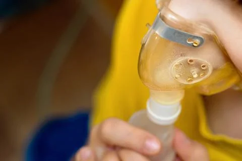 Child upper closeup view makes inhalation at home with nebulizer on out of fo Foto stock