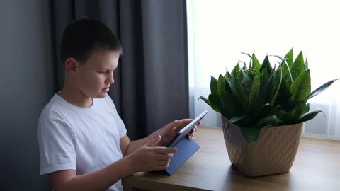 Child uses electronic tablet for homework engaging in digital education Boy Stock Footage 265867744