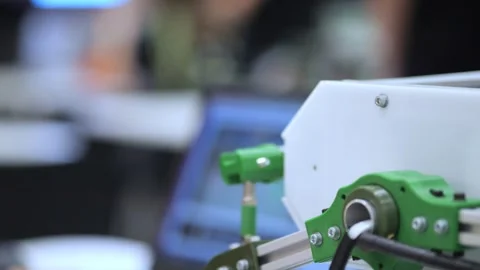 Child uses hands to guide small green robotic vehicle with visible gears Stock Footage 345376541