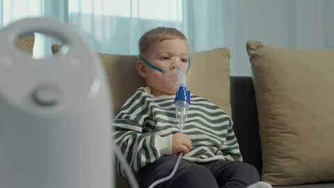 Child uses nebulizer with saline solution to treat cough at home Stock Footage 346706649
