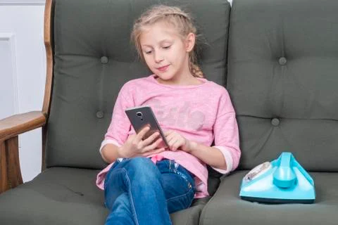 Child uses smartphone while sitting on couch Stock Photos