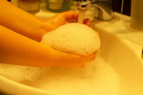 The child uses soap and washes his hands under the tap with water Stock Photos