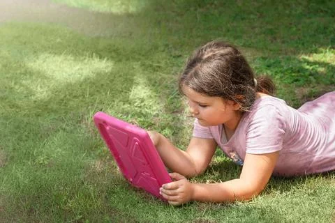 A child uses a tablet on the grass Stock Photos