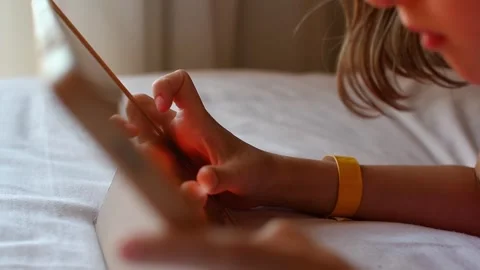 Child uses touchscreen tablet on hotel bed during quiet indoor leisure, family Stock Footage 337663756