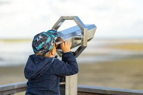 Child using a binocular viewer to explore the landscape at a coastal observation Stock Photos