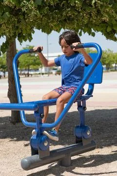 Child using a blue exercise machine in an outdoor gym Stock-Fotos