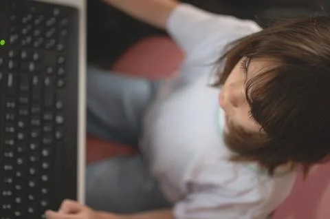 Child using a computer at home during the afternoon Stock Photos