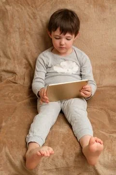 Child using digital tablet, a boy interacting with a device. Early childhoo.. Stock Photos