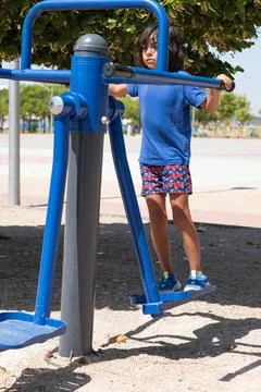 Child using an elliptical cross trainer in an outdoor gym Stock Photos