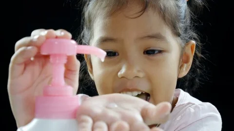Child using lotion dispenser bottle on black background. 4K in studio shot Stock Footage 79967122